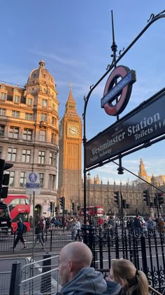 the big ben clock tower towering over the city of london as people walk on the sidewalk