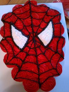 a spiderman cake with red icing and white frosting