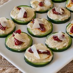 cucumbers with cream cheese and jelly on them sitting on a white platter