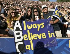 a group of people holding up a sign in front of a crowd at a football game