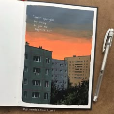 an open book with a painting of buildings and a pen