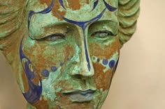 a close up of a statue with blue and green paint on it's face