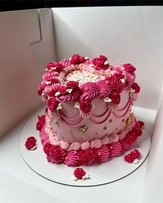 a pink and white cake sitting on top of a table next to a cardboard box