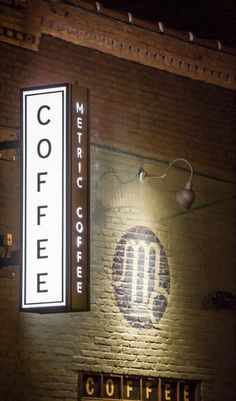 the coffee sign is lit up on the brick wall