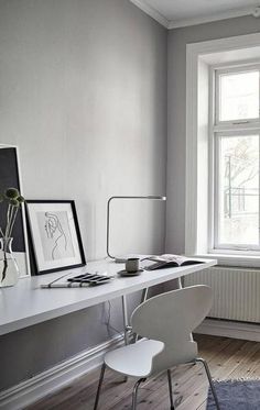 a white desk and chair in front of a large window with pictures on the wall