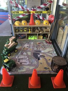 there is a toy train set on the ground next to traffic cones and construction signs