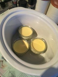 three jars are sitting in the middle of a white bowl with four lids on it