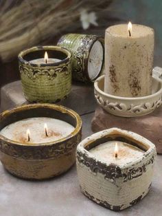 four candles sitting on top of each other in small bowls next to rocks and vases