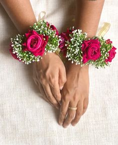 two brides holding hands with red roses and baby's breath flowers on them