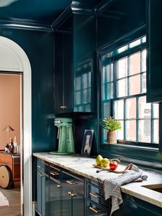 a kitchen with blue walls and wooden cabinets, an island countertop and potted plant on the window sill