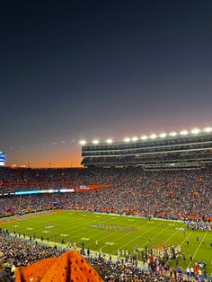 a football stadium filled with lots of people on it's sidelines at night