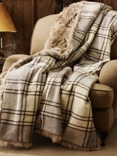 a dog sitting on the floor next to a chair with a blanket draped over it