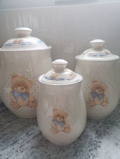 three ceramic jars with teddy bears painted on the lids and bottom, sitting on a counter