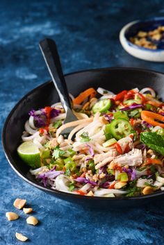 a black bowl filled with vegetables and noodles