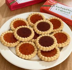 four small pies on a plate next to a carton of jelly