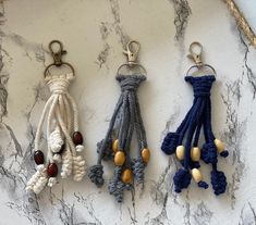 three key chains hanging from ropes on a marble counter top with beads and wood beads