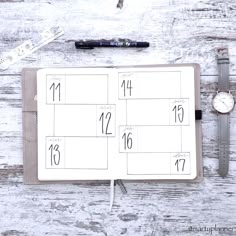 an open planner with the numbers on it and a watch next to it, sitting on top of a wooden table