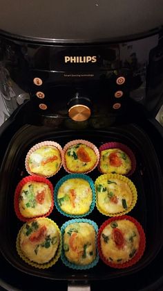 several small muffins sitting in the bottom of an air fryer with different toppings