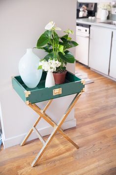 a green tray with white flowers and a potted plant sitting on top of it