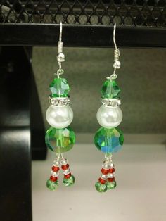 the earrings are decorated with green, red and white beads