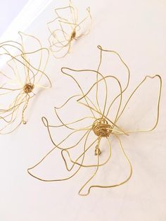 three pieces of gold wire sitting on top of a white tablecloth covered in papers