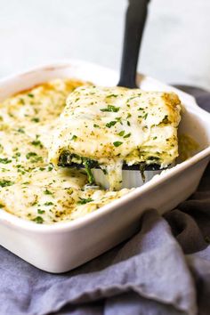 a casserole dish with broccoli and cheese in it on a blue towel