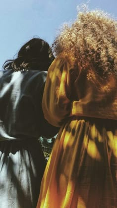 two women standing next to each other looking at the sky with their hands on their hips