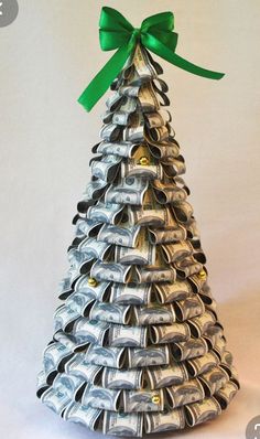 a small silver christmas tree made out of metal cans with a green bow on top