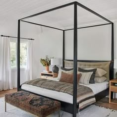 a four poster bed in a bedroom with white walls