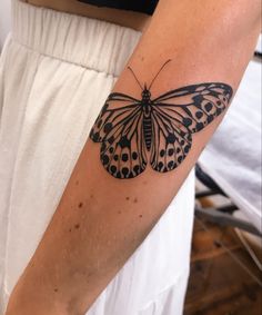 a black and white butterfly tattoo on the right arm, with dots all over it