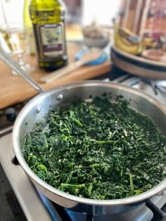 a pan filled with greens sitting on top of a stove