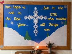 a wooden table topped with a lit candle next to a large poster on the wall