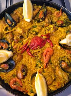 a pan filled with seafood and rice on top of a stove