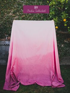 a pink and white blanket sitting on top of a lush green field