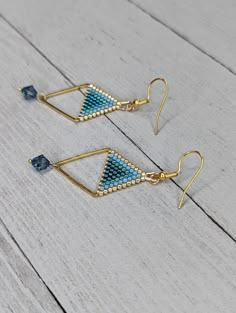 two pairs of gold and blue beaded triangle earrings on white wooden background, closeup