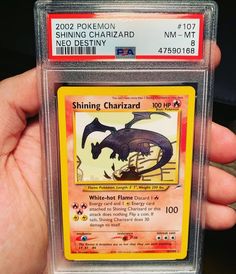 someone holding up a pokemon trading card in their hand with the name shining charizard on it