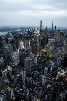 an aerial view of the city at night with skyscrapers lit up and buildings in the foreground