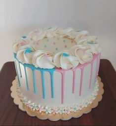 a cake with white frosting and blue icing drips sitting on top of a wooden table