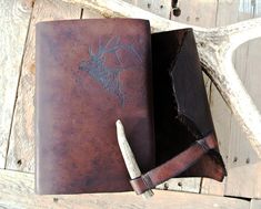 an old leather journal with a deer head on it and a pen laying next to it