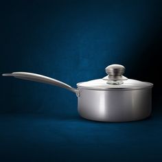 a silver pan with a lid on a dark blue background and a spoon in it