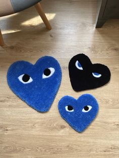 three blue and black heart shaped rugs with eyes on them sitting on a wooden floor