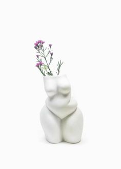 a small white vase with flowers in it