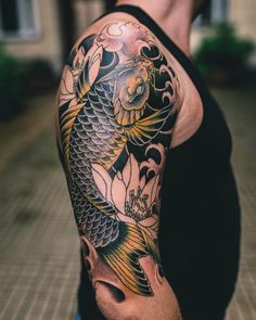 a man with a tattoo on his arm is standing in front of a building and has a koi fish on it