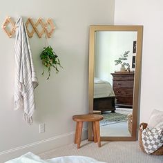 a bedroom with a mirror, stool and potted plant