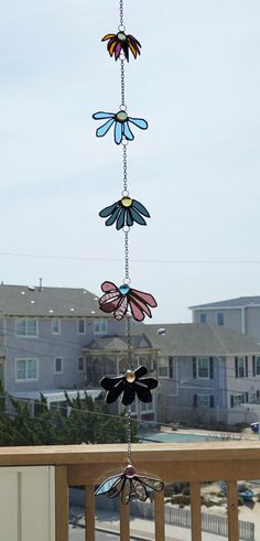 a wind chime hanging from the side of a wooden fence with houses in the background