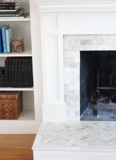 a white fireplace with bookshelves in the background