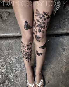 a woman's legs with butterflies and flowers tattooed on her leg, next to stairs