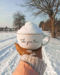 a person holding a cup with snow on it and the words take your time written in it