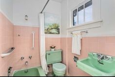 a bathroom with pink and green walls, toilet, sink and bathtub in it