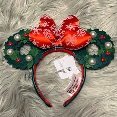 a mickey mouse ears headband with red and green decorations on top of white fur